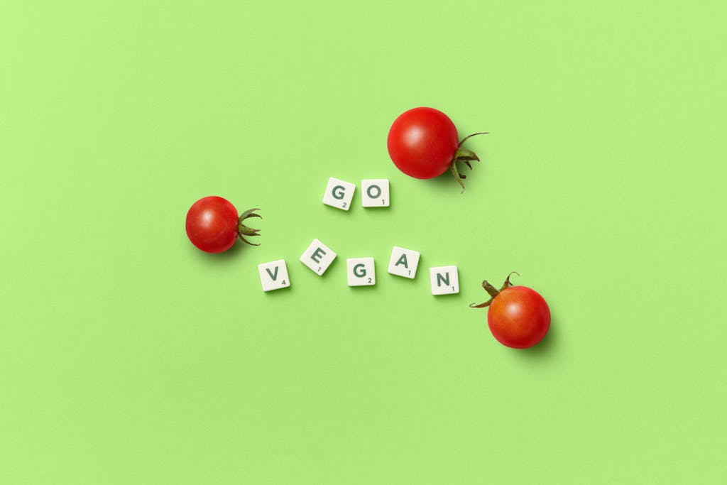 Minimalist image of cherry tomatoes and 'Go Vegan' text on a green background.